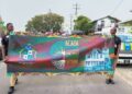 Two students carry the Georgetown Mayor and City Council banner during the Black History Month March on February 27, 2026, proudly displaying the message “Black History: Honouring the Past, Inspiring the Future” as participants proceeded from City Hall to Independence Park.