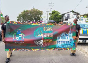 Two students carry the Georgetown Mayor and City Council banner during the Black History Month March on February 27, 2026, proudly displaying the message “Black History: Honouring the Past, Inspiring the Future” as participants proceeded from City Hall to Independence Park.