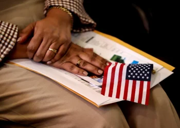 A new citizen holds an American flag during a naturalization ceremony in Metheun, Mass., in 2024.David L. Ryan / Boston Globe via Getty Images