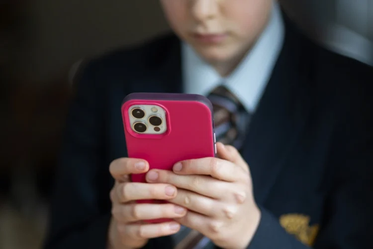 A 12-year-old school boy uses an iPhone in Bath, England in 2024. Matt Cardy / Getty Images