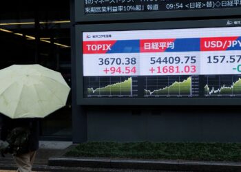A pedestrian looks at a stock quotation board showing the Topix average, the Nikkei share average and the exchange rate between Japanese yen and U.S. dollar outside a brokerage in Tokyo. /Kim Kyung-Hoon/Reuters