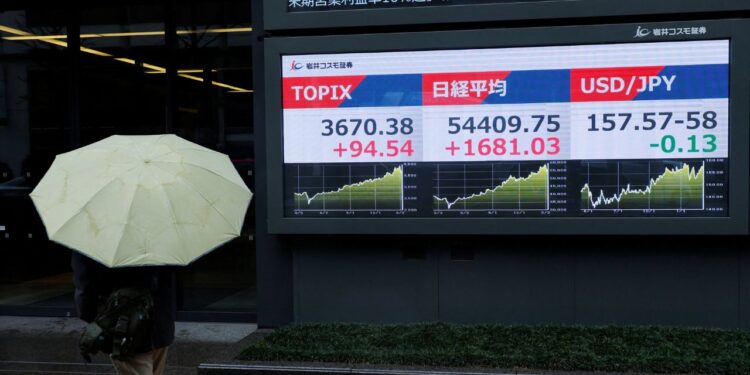 A pedestrian looks at a stock quotation board showing the Topix average, the Nikkei share average and the exchange rate between Japanese yen and U.S. dollar outside a brokerage in Tokyo. /Kim Kyung-Hoon/Reuters