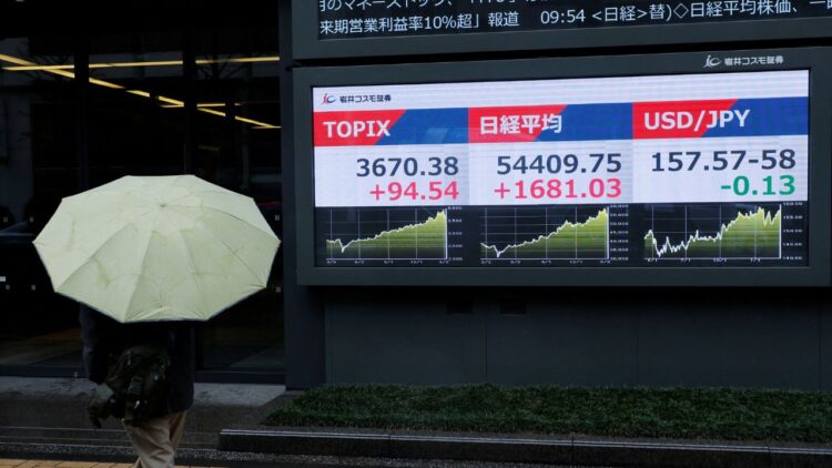 A pedestrian looks at a stock quotation board showing the Topix average, the Nikkei share average and the exchange rate between Japanese yen and U.S. dollar outside a brokerage in Tokyo. /Kim Kyung-Hoon/Reuters