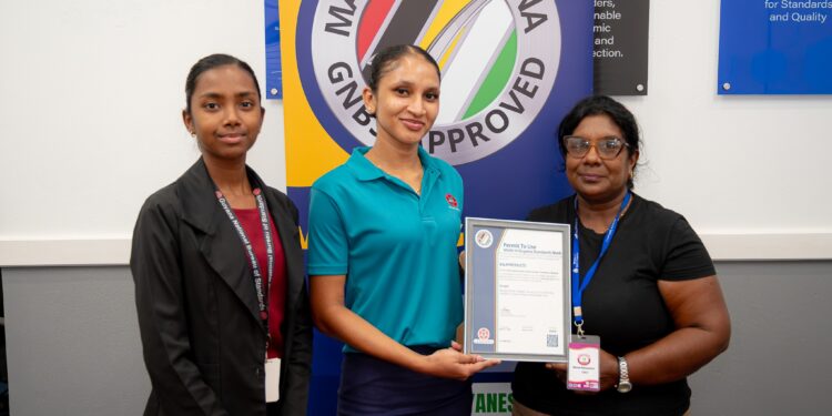 The-Made-in-Guyana-Certificate-being-handed-over-by-GNBS-Administrative-Clerk-Faith-Phillips-and-Technical-Officer-Rachel-Cecil-to-the-Proprietor-of-BR-Products-Budwatty