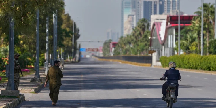 An Army soldier, left, walk as a police officer drives motorcycle on an empty road ahead of  second round of negotiations between U.S. and Iran, in Islamabad, Pakistan Monday April 20, 2026 (AP Photo/ Amjum Naveed)