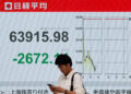 [1/2]A pedestrian stands in front of a stock quotation board showing the Nikkei share average outside a brokerage in Tokyo, Japan, June 8, 2026. REUTERS/Kim Kyung-Hoon Purchase Licensing Rights