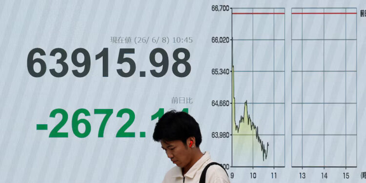 [1/2]A pedestrian stands in front of a stock quotation board showing the Nikkei share average outside a brokerage in Tokyo, Japan, June 8, 2026. REUTERS/Kim Kyung-Hoon Purchase Licensing Rights