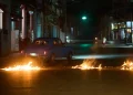 People drive a classic American car through a barricade set up by residents protesting against prolonged power outages in Havana, Cuba, Wednesday, May 13, 2026. (AP Photo/Ramon Espinosa)