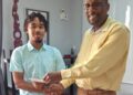 CEO of Nations University, Dr. Dexter Phillips, presents Emmanuel Pereira with the contribution from School of the Nations