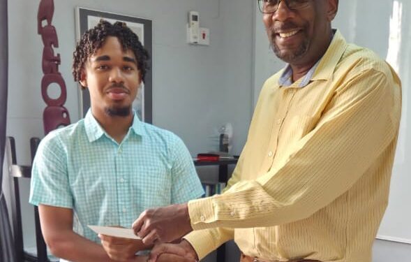 CEO of Nations University, Dr. Dexter Phillips, presents Emmanuel Pereira with the contribution from School of the Nations