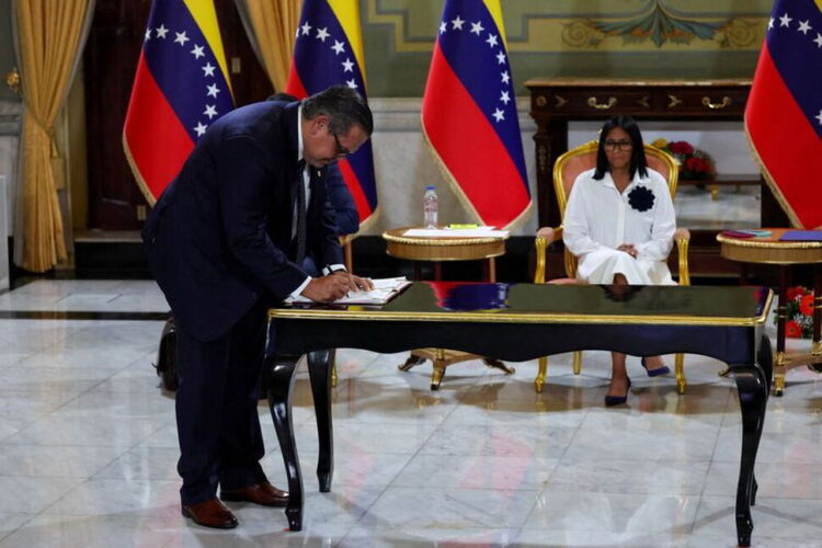 FILE PHOTO: Venezuela's interim President Delcy Rodriguez looks on as Mariano Vela, President of Chevron in Venezuela signs an oil agreement between Chevron and Venezuela's state oil company PDVSA, in Caracas, Venezuela April 13, 2026. REUTERS/Leonardo Fernandez Viloria/File Photo