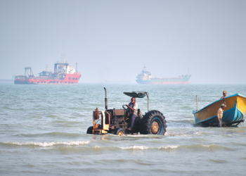 A tractor pulls a boat from the sea as commercial vessels are anchored in the Strait of Hormuz off Bandar Abbas, Iran, on Monday. RAZIEH POUDAT/ISNA VIA AP
