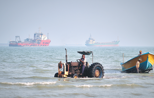 A tractor pulls a boat from the sea as commercial vessels are anchored in the Strait of Hormuz off Bandar Abbas, Iran, on Monday. RAZIEH POUDAT/ISNA VIA AP