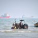 A tractor pulls a boat from the sea as commercial vessels are anchored in the Strait of Hormuz off Bandar Abbas, Iran, on Monday. RAZIEH POUDAT/ISNA VIA AP