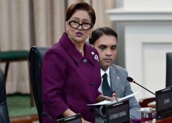fighting against crime: Prime Minister Kamla Persad-Bissessar delivers a statement during yesterday’s sitting of Parliament. At right is Public Utilities Minister Barry Padarath. —Photo: JERMAINE CRUICKSHANK