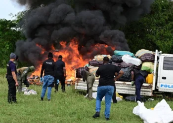 beating the heat: Commissioner of Police Allister Guevarro, centre, quenches his thirst as he oversees the destruction of large quantities of illegal drugs during a TTPS exercise yesterday at the Caroni Cremation Site. —Photo: JERMAINE CRUICKSHANK