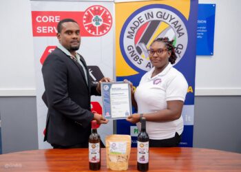 GNBS Head of Certification Services (ag), Keon Rankin, handing over the certificate to Managing Director of Sand Flower Products, Xuxa Lowe