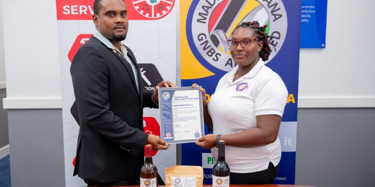 GNBS Head of Certification Services (ag), Keon Rankin, handing over the certificate to Managing Director of Sand Flower Products, Xuxa Lowe