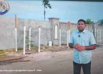Opposition Leader Azruddin Mohamed standing in front of the wall at Leonora, West Coast Demerara (screen grab photo)