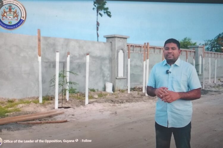 Opposition Leader Azruddin Mohamed standing in front of the wall at Leonora, West Coast Demerara (screen grab photo)