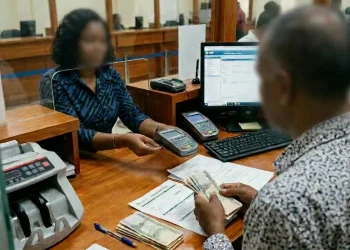 A bank teller assisting a customer with currency and documents at Guyana Development Bank