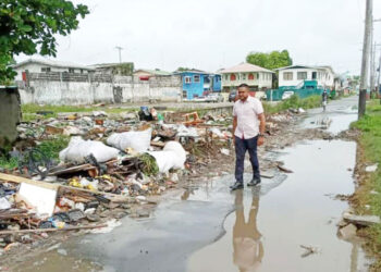 then PPP Minister of Local Government Nigel Dharamlall walks by 'inspects' garbage in the city (Guyana Chronicle) photo)