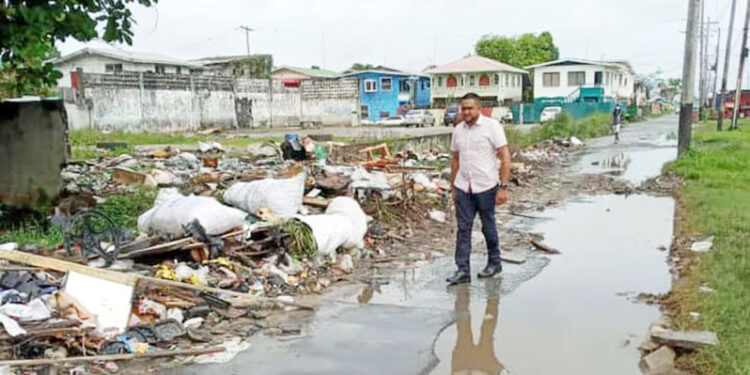 then PPP Minister of Local Government Nigel Dharamlall walks by 'inspects' garbage in the city (Guyana Chronicle) photo)