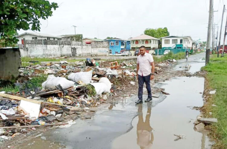 then PPP Minister of Local Government Nigel Dharamlall walks by 'inspects' garbage in the city (Guyana Chronicle) photo)