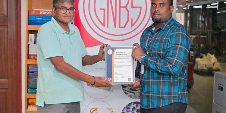 GNBS Head of Certification Services (ag), Keon Rankin, handing over the certificate to Deputy Factory Manager at Gafsons Industries, Jitendra Mishrah